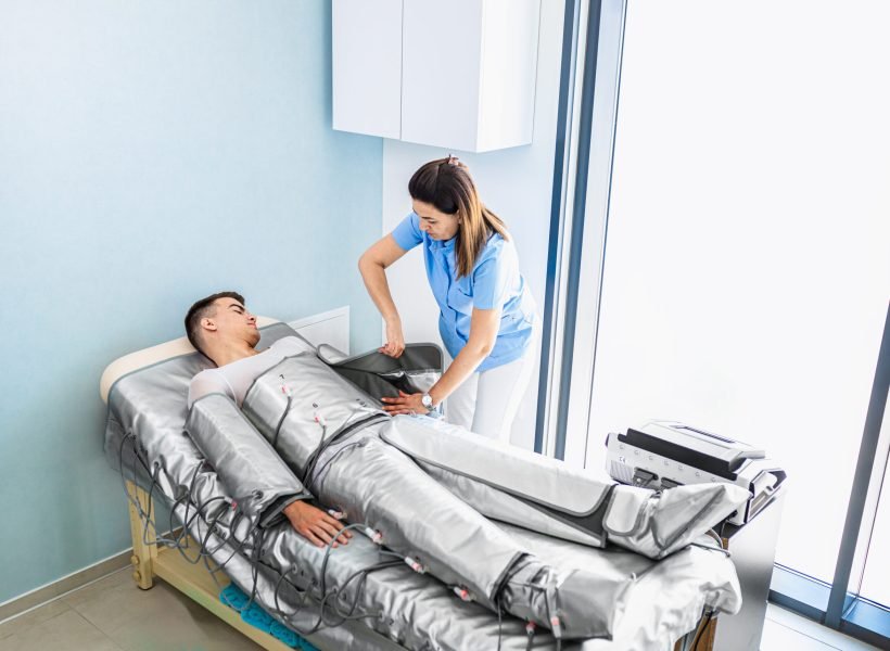 Beautician therapist applying pressotherapy treatment beauty salon to young man.