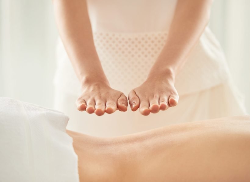 Hands of woman doing reiki healing treatment on female patient