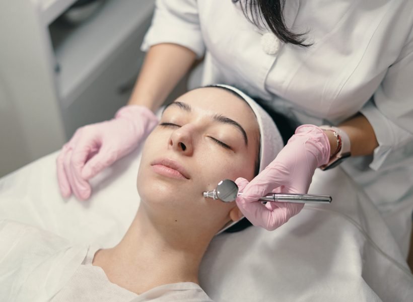 Model with closed eyes and hand's of doctor. Rejuvenating facial treatment. Model getting lifting therapy massage in a beauty SPA salon. Cosmetological clinic, procedure.